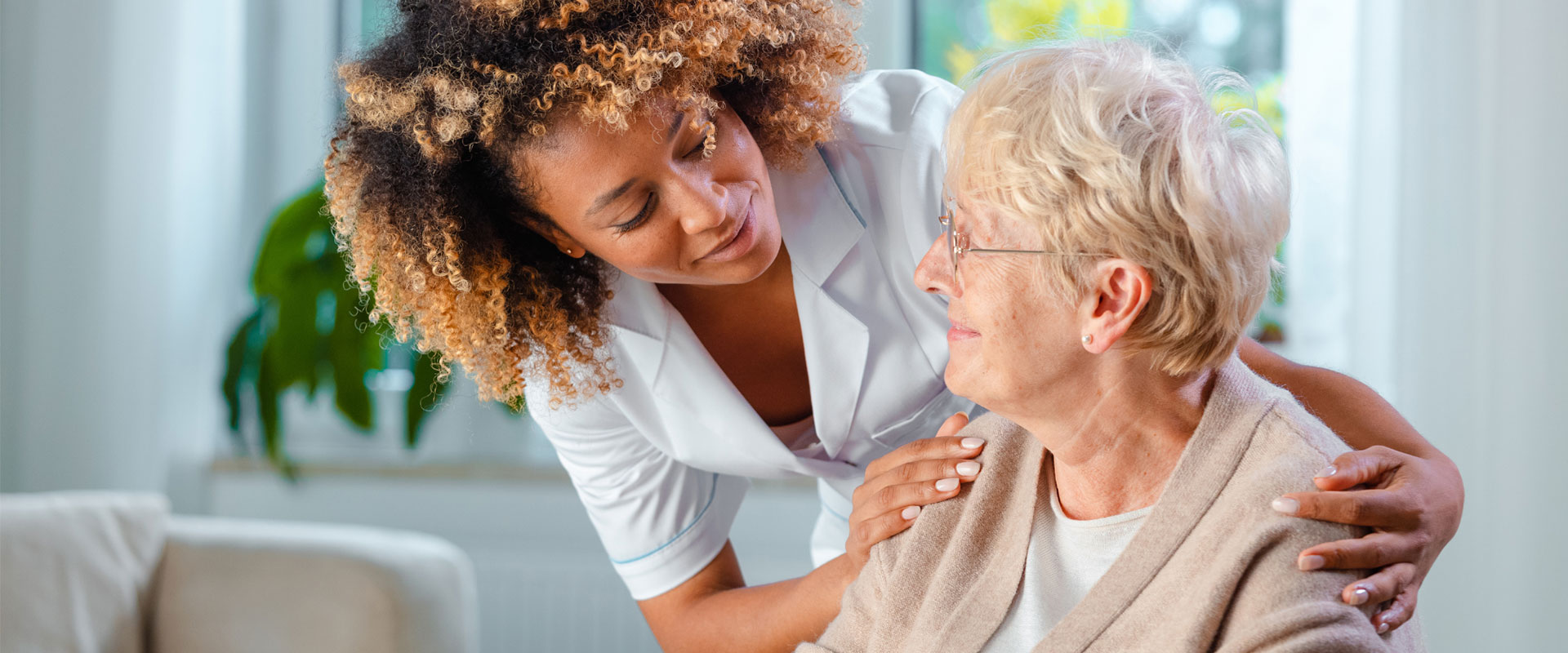 Betreuungskraft legt beruhigend die Hand auf Seniorin.