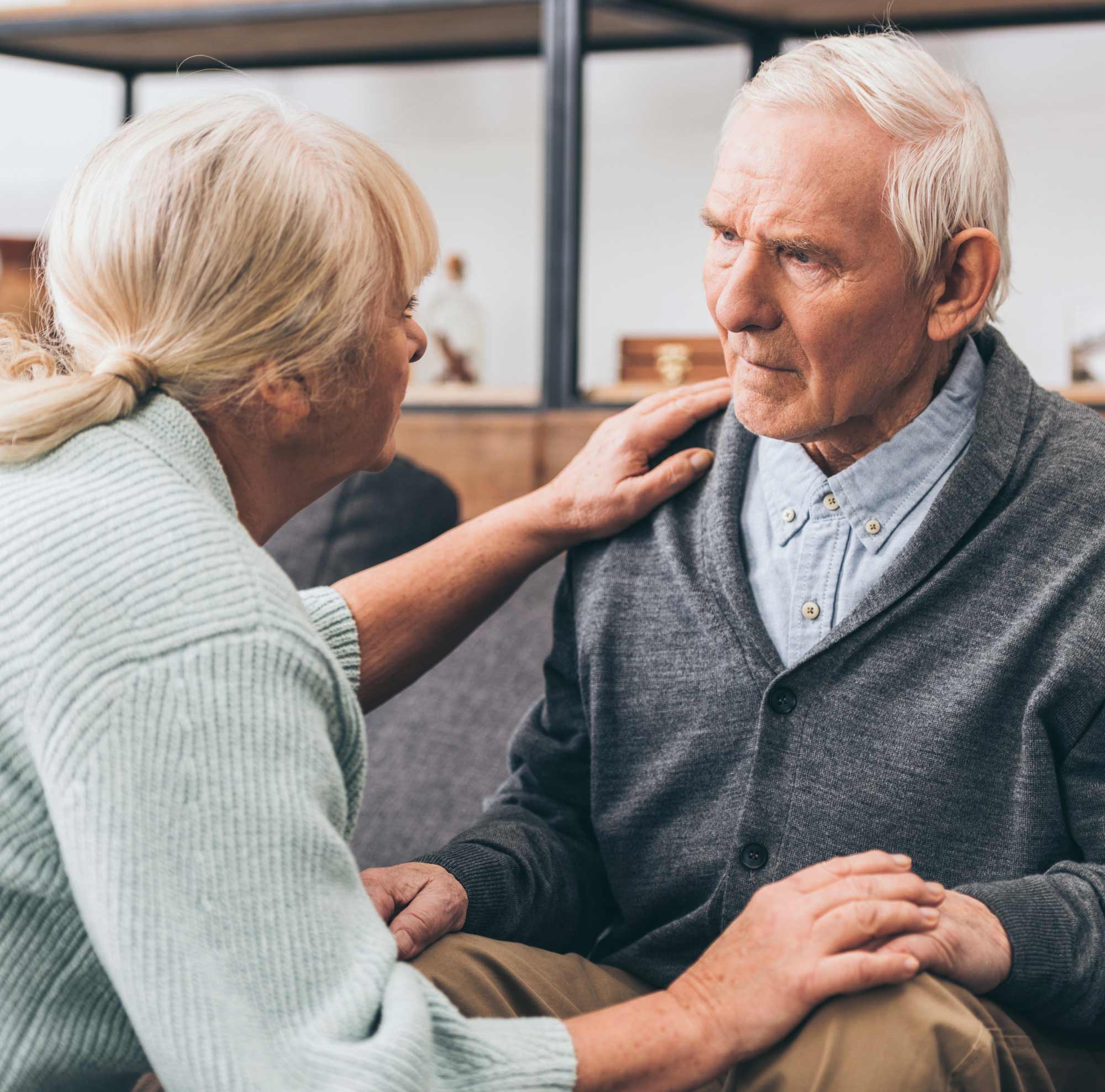 Ältere Frau beruhigt ihren demenzkranken Partner durch eine einfühlsame Geste.
